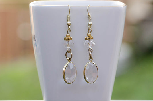 Clear Oval Glass Dangle Earrings displayed on a tea cup.
