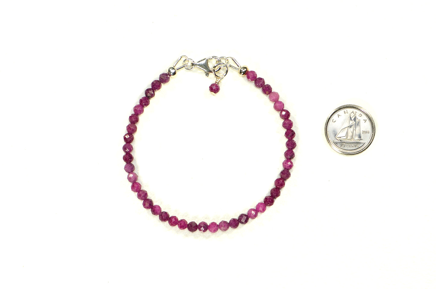 Faceted Ruby Bracelet with Sterling Silver Clasp beside a dime.