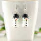 Snowman Glass Bead Earrings displayed on a tea cup.
