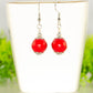 12mm Red Howlite Dangle Earrings displayed on a tea cup.