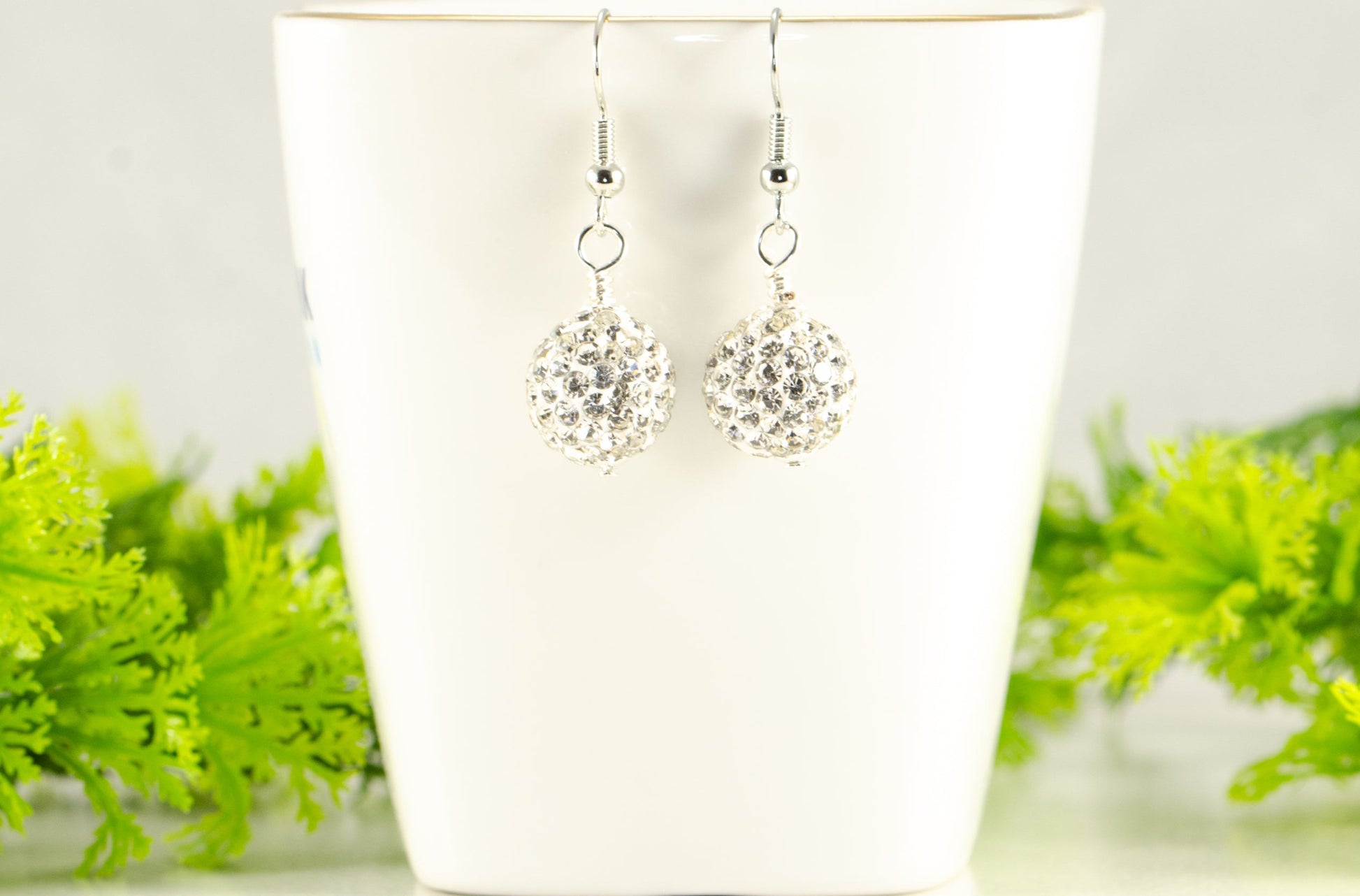 12mm Rhinestone Disco Ball Earrings displayed on a tea cup.