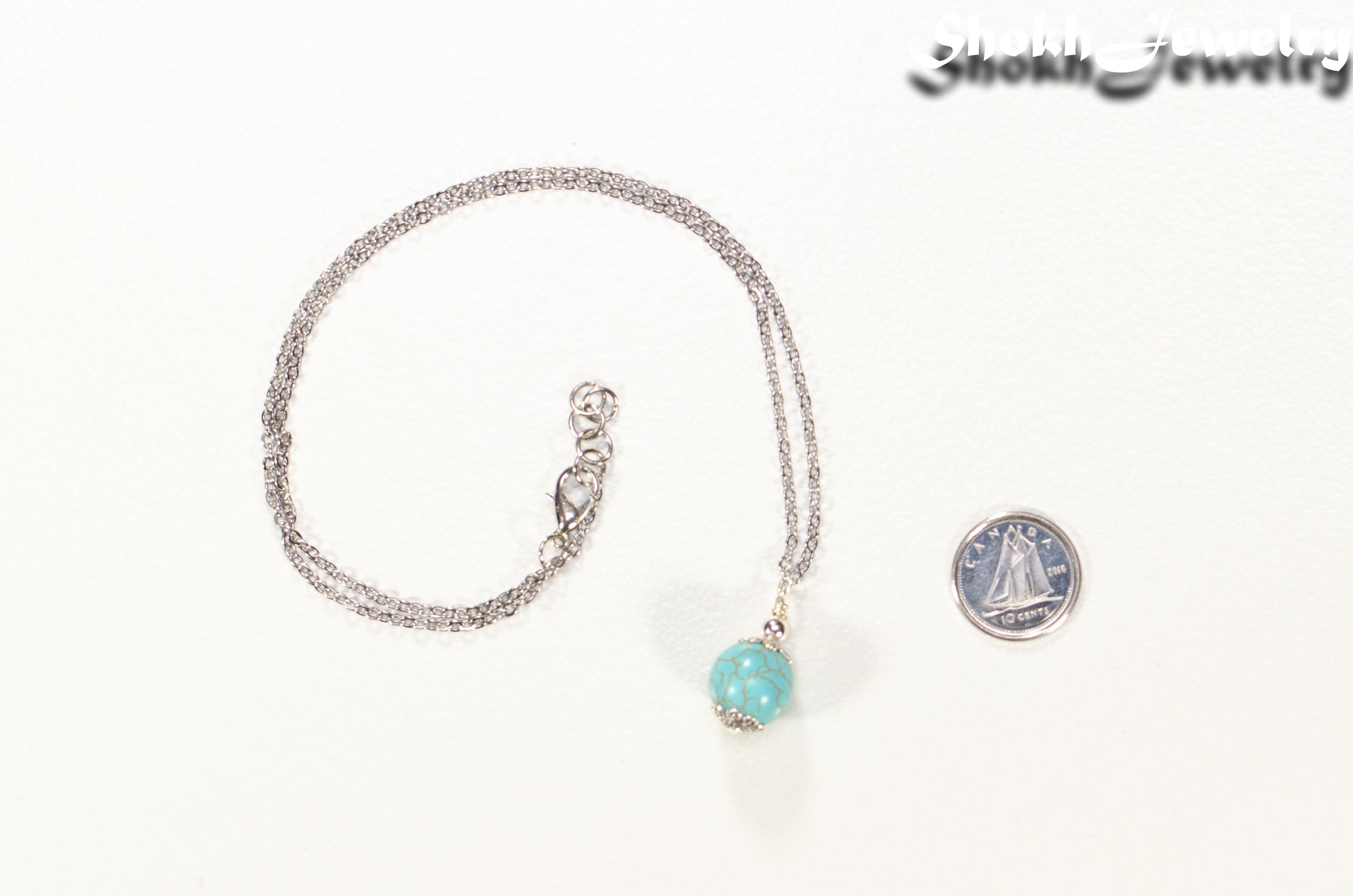 12mm Turquoise Howlite Pendant Necklace beside a dime.