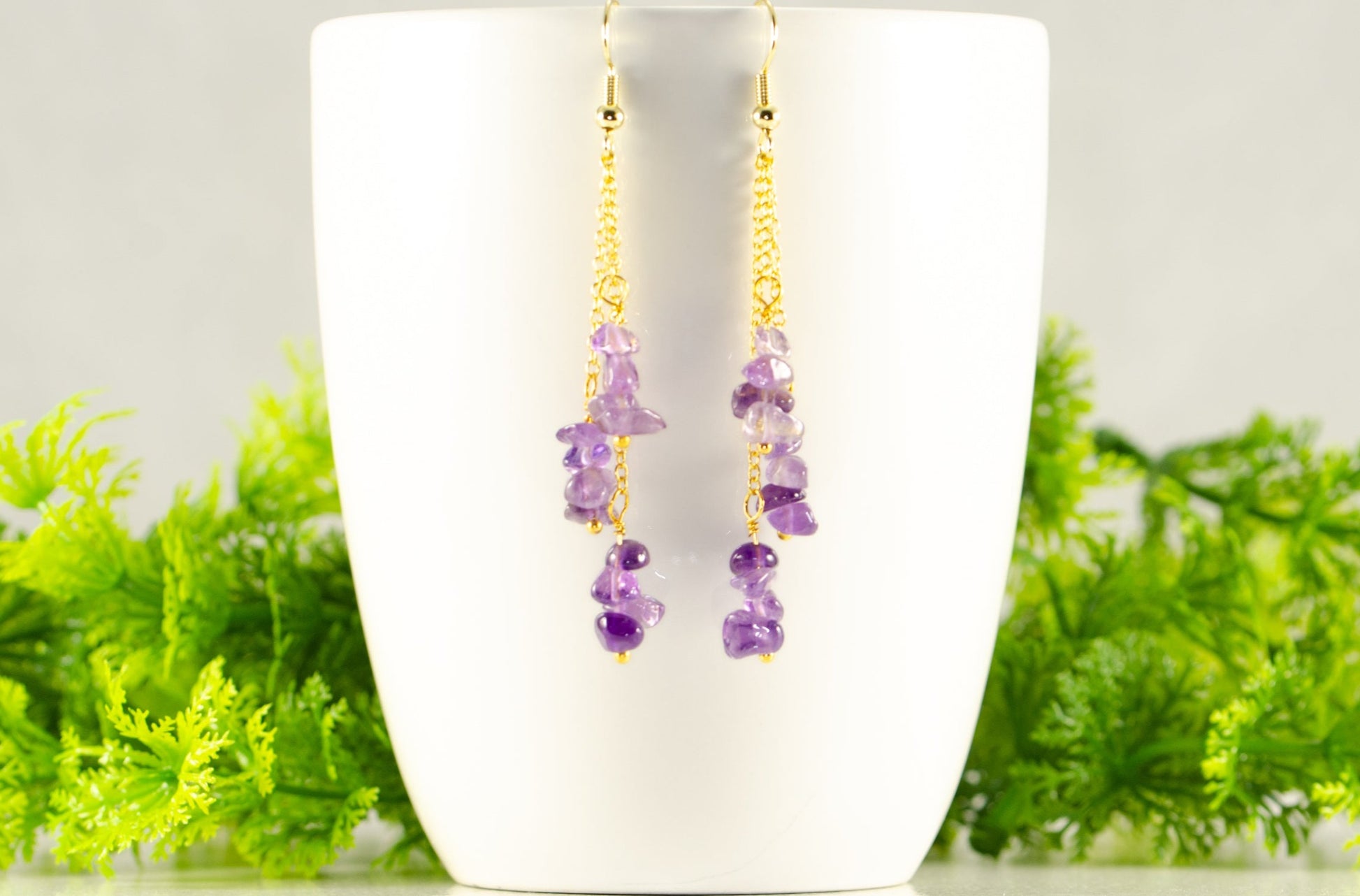 Long Gold Plated Chain and Amethyst Crystal Chip Earrings displayed on a coffee mug.