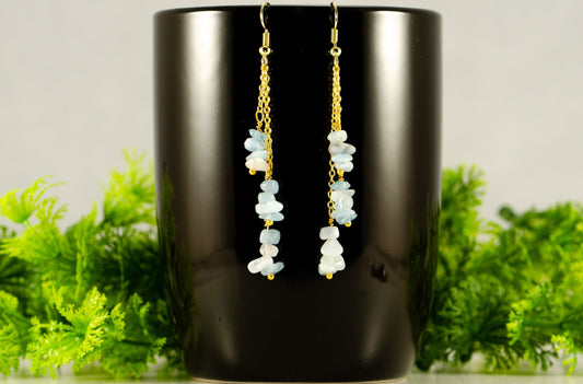 Long Gold Plated Chain and Aquamarine Crystal Chip Earrings on a coffee mug.