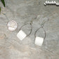 Miniature Toilet Paper Roll Earrings beside a dime.