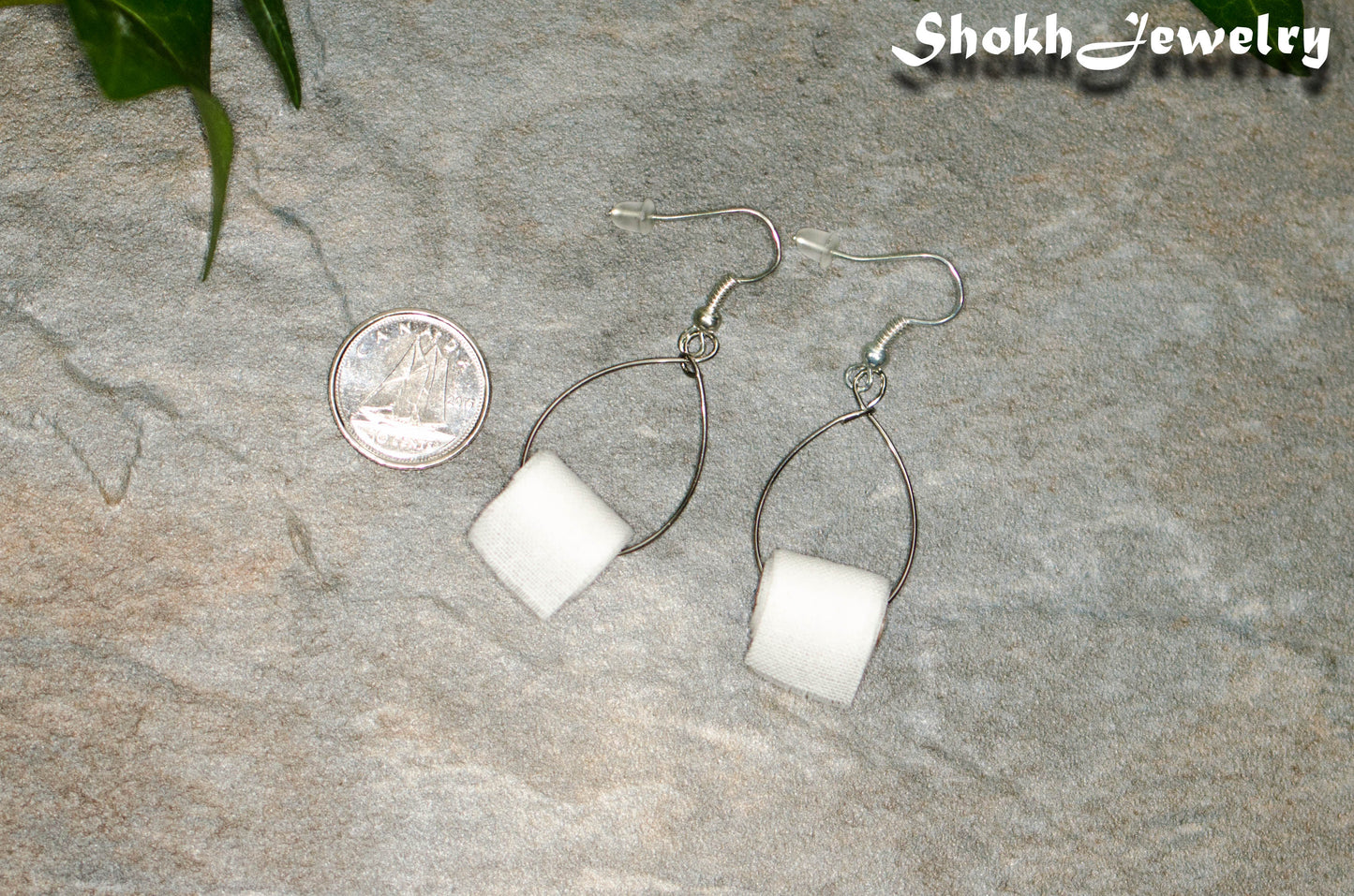 Miniature Toilet Paper Roll Earrings beside a dime.