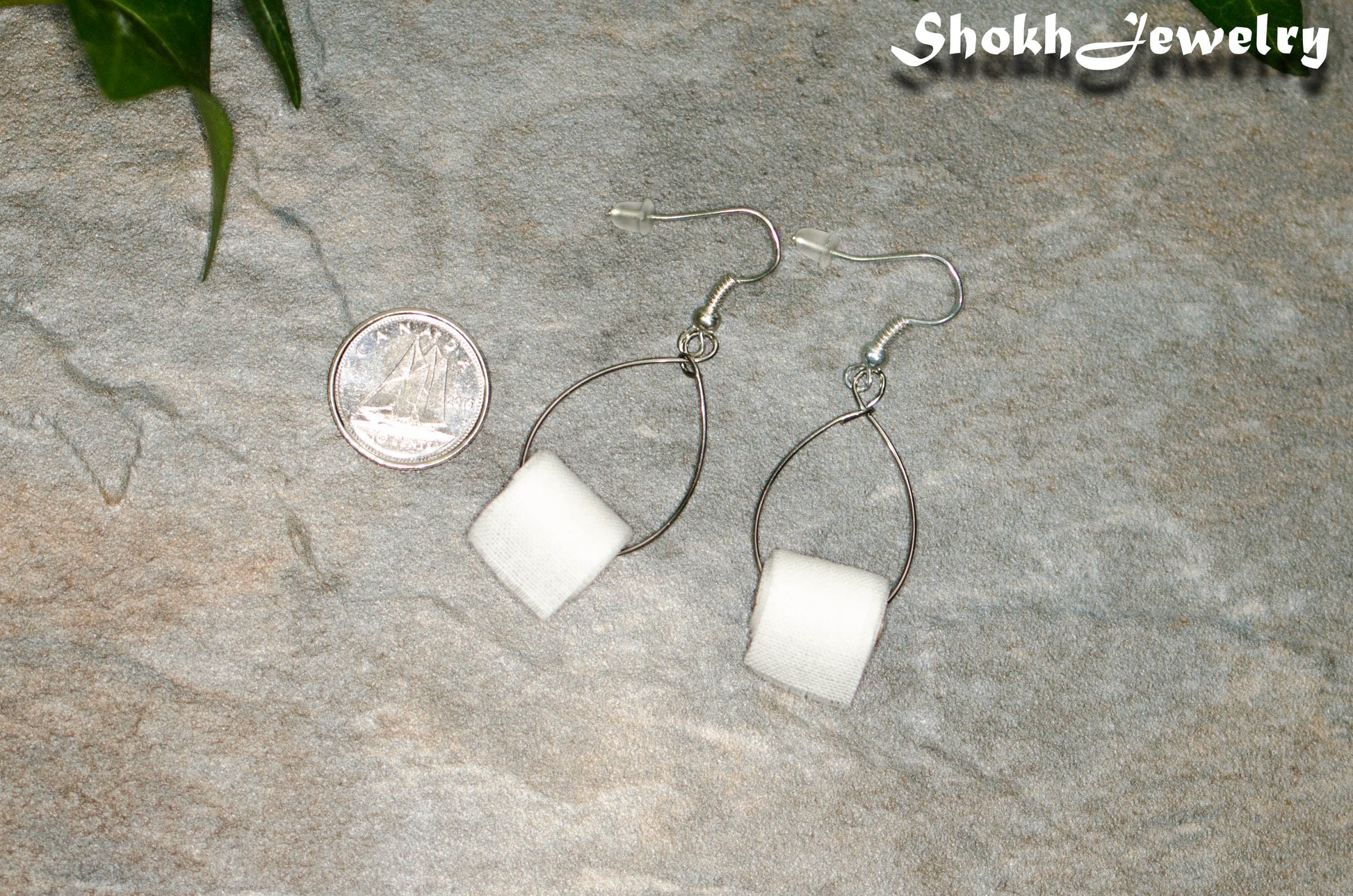 Miniature Toilet Paper Roll Earrings beside a dime.