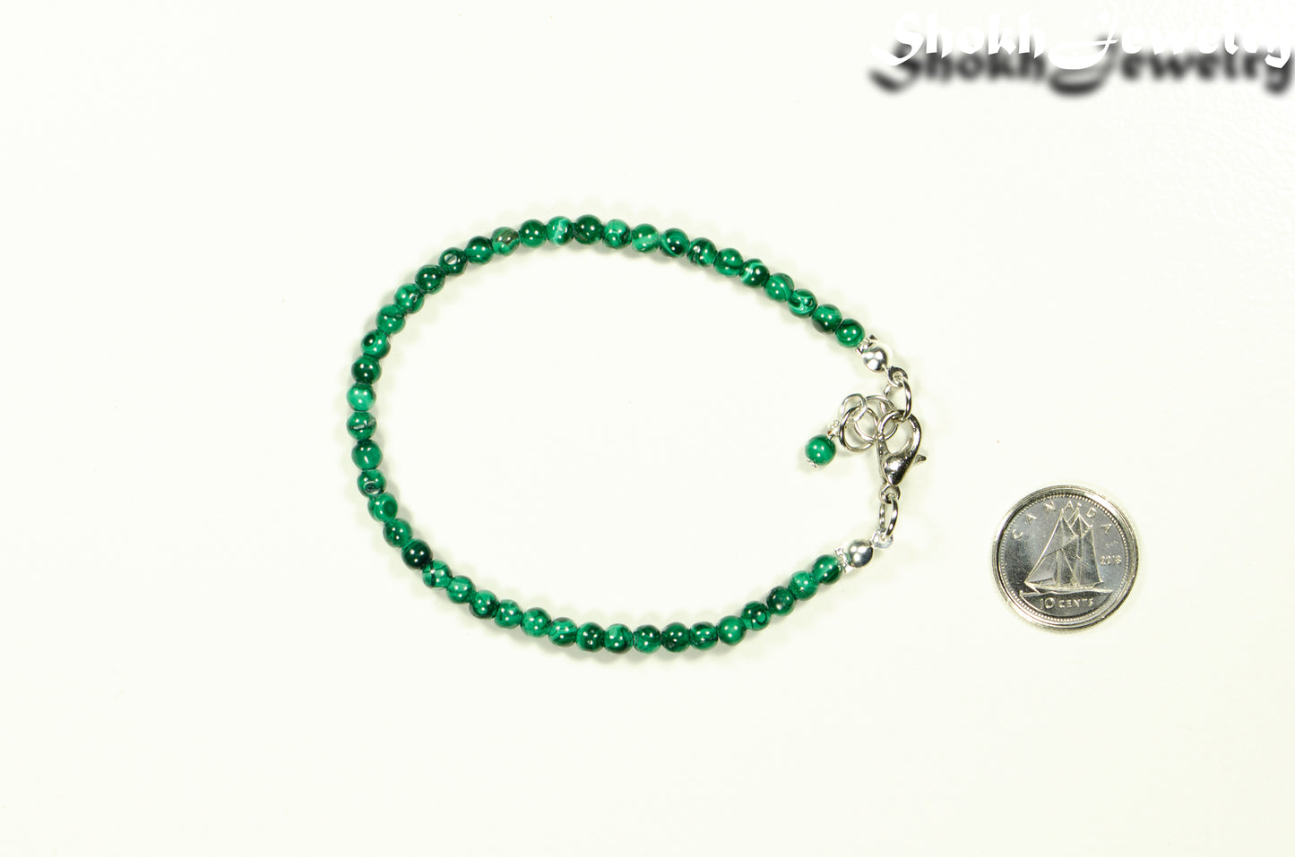 3mm Natural Malachite Bracelet with Clasp beside a dime.