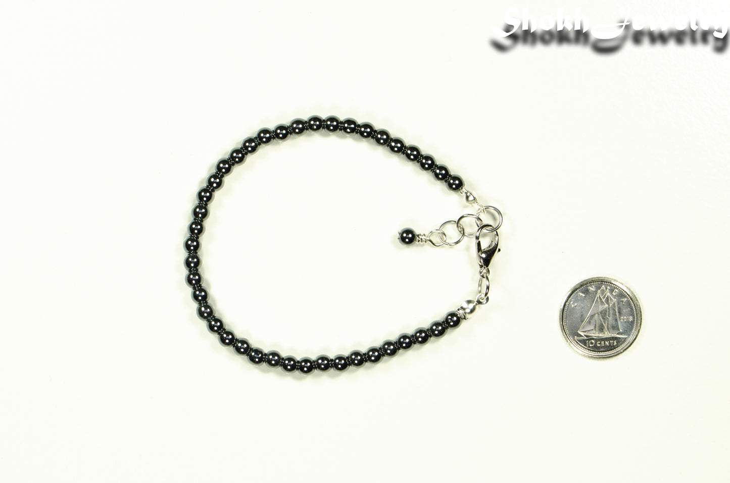 4mm Hematite Stone Bracelet with Clasp beside a dime.