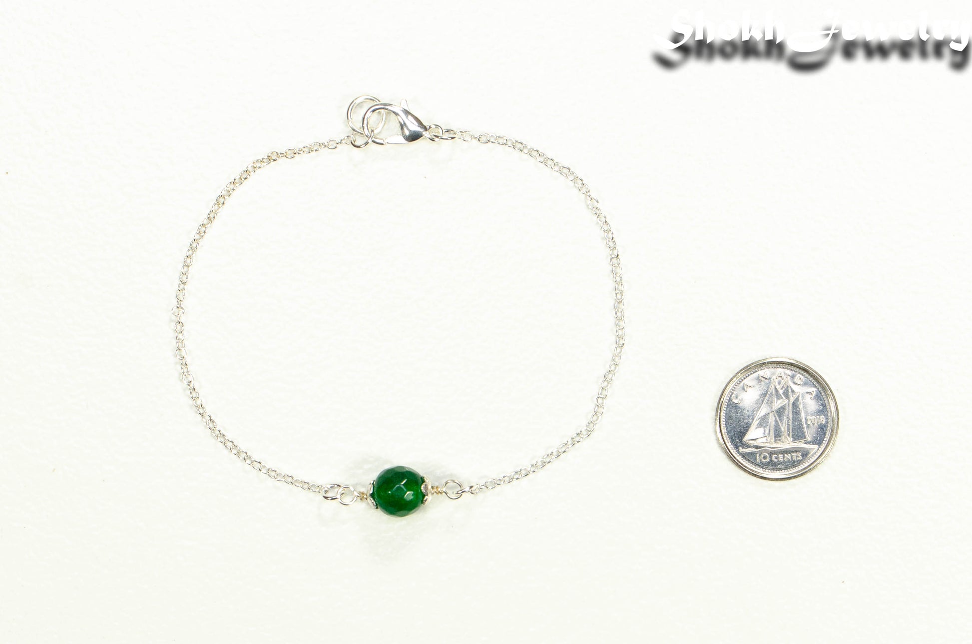 Minimal Green Emerald Bracelet beside a dime.