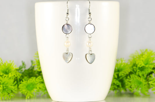 Grey Seashell and White Pearl Earrings displaed on a coffee mug.