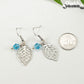 Filigree Leaf Charm and Aqua Blue Glass Crystal Earrings beside a dime.