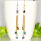 Sparkly Hematite Star and Gold Chain Earrings displayed on a white mug.