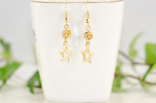 Sparkly Rhinestone and Gold Star Earrings displayed on a tea cup.